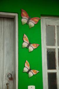 three butterflies on a green wall next to a door at Pérola da Mata in Boicucanga