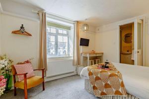 a bedroom with a bed and a chair and a window at 1605 by the sea in Falmouth