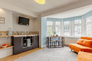 a living room with an orange couch and a tv at 1605 by the sea in Falmouth +5 photos