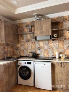 Waschmaschine und Trockner in einer Küche mit Holzschränken in der Unterkunft RO METRO in Gjumri