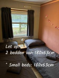 a bedroom with two beds and a desk and a window at Prachtige stacaravan met heerlijke overkapping in Eext