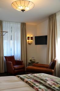 a hotel room with two chairs and a bed and a television at Hotel Garni Villa Arrisja in Eefde