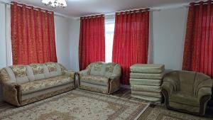 a living room with two chairs and red curtains at Krat in Osh