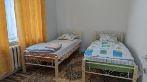 two twin beds in a room with a window at Krat in Osh