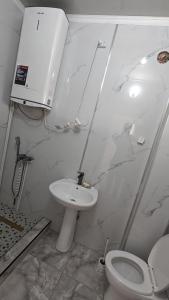 a white bathroom with a toilet and a sink at Krat in Osh