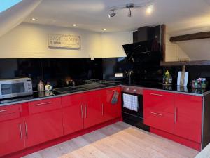 a kitchen with red cabinets and a microwave at LE CHAMPENOIS-Appartement central près de l' Avenue de Champagne in Épernay