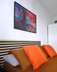 a bed with orange pillows and a television on the wall at Alma Del Sur Tenerife in Arona