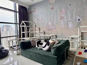 a room with a green couch with a cow pillow on it at Azure Residences, PJ Paradigm By Kiddie Space, Kids Friendly in Petaling Jaya +32 photos
