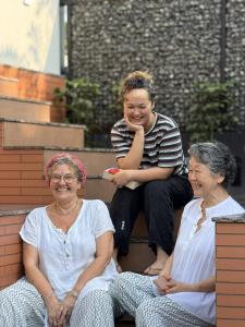 three women sitting on the steps of a building at Oblue Private Pool Villa in Cherai Beach +2 photos