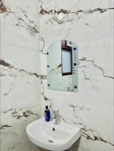 a white bathroom with a sink and a mirror at Vogue- Lavish collection in Zirakpur +15 photos