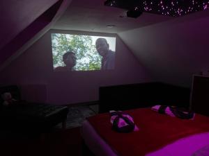 a room with a bed and a tv with two men at Étoiles et Désirs in Kermaria-Sulard