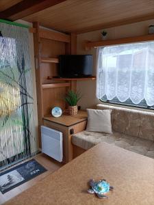 a small living room with a couch and a tv at Mobil home inter in Berck-sur-Mer