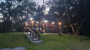 a small tree house with a staircase in the grass at Holo Pousada Vale Encantado in Rancho Queimado