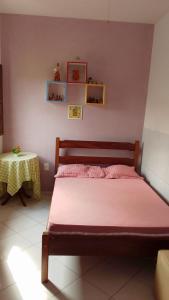 a bedroom with a bed with a pink sheets and a table at Casa Rosa da Ilha - Suíte Confortável com Ventilador e Jardim in Vera Cruz de Itaparica