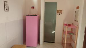 a pink refrigerator in the corner of a room at Casa Rosa da Ilha - Suíte Confortável com Ventilador e Jardim in Vera Cruz de Itaparica