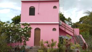 a pink house with a staircase leading up to it at Casa Rosa da Ilha - Suíte Confortável com Ventilador e Jardim in Vera Cruz de Itaparica +12 photos