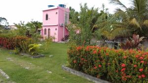 a pink house with a bunch of flowers in a yard at Casa Rosa da Ilha - Suíte Confortável com Ventilador e Jardim in Vera Cruz de Itaparica