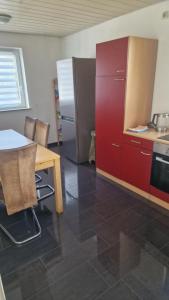 a kitchen with red cabinets and a table and a refrigerator at Rooms & Apartments Schwäbisch Gmünd in Schwäbisch Gmünd