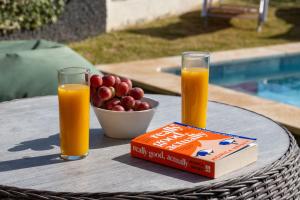 a table with two glasses of orange juice and a box of fruit at Villa Liana by LovelyStay in Ponta do Sol