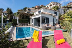 a villa with a swimming pool and two lawn chairs at Villa Liana by LovelyStay in Ponta do Sol