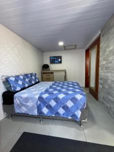 a bedroom with a blue bed and a tv at Pousada aconchego in Imbituba