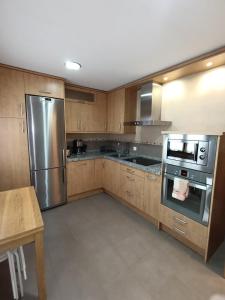 a kitchen with wooden cabinets and stainless steel appliances at Piso Rualte in Ávila