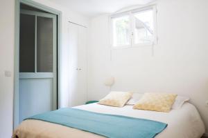 a white bedroom with a bed and a window at Malot 34 in Montreuil