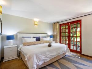 a bedroom with a large white bed and a red door at The Horseshoe Guesthouse in Midrand