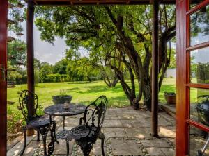 a patio with a table and chairs and a tree at The Horseshoe Guesthouse in Midrand