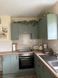 a kitchen with white cabinets and a black oven at StoneHaven Townhouse in Donegal
