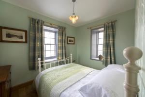 ein Schlafzimmer mit einem Bett und zwei Fenstern in der Unterkunft Tangle Tower in Inverness