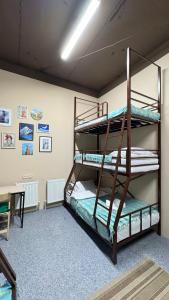 two bunk beds in a room with a desk at Sky Tau Hostel in Almaty