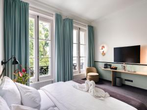 a hotel room with a bed and a desk and windows at Aussen Alster Hotel in Hamburg