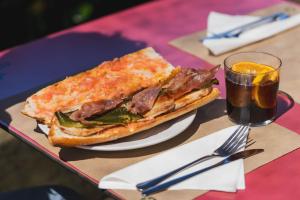 a sandwich on a plate next to a glass of soda at Camping Ridaura in Llagostera