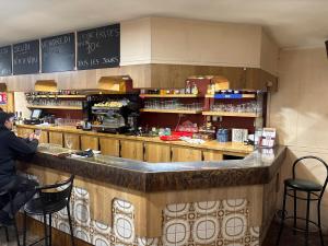 a man standing at the counter of a restaurant at Hôtel café des cours in Cébazat