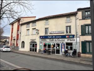 a building on the side of a street with a man sitting in a chair outside at Hôtel café des cours in Cébazat