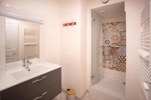 a white bathroom with a sink and a shower at T3 Cosy - Art Déco in Villefranche-de-Rouergue +11 photos