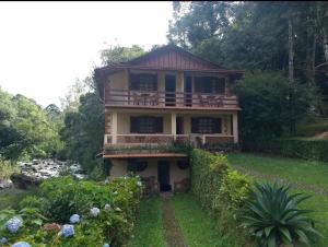a house with a balcony and a yard at Pousada Céu aberto in Núcleo Mauá