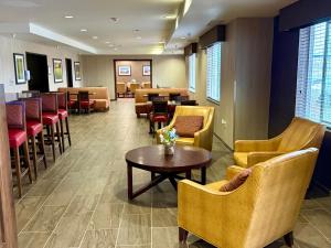 a waiting room with chairs and a table and a bar at Inn at Hunters Run in Watford City