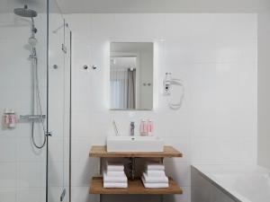 a white bathroom with a sink and a shower at Numa Amsterdam Docklands in Amsterdam