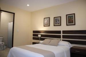 a bedroom with a large bed and two pictures on the wall at Casa 3 Torres, Calle 76 in Mérida +31 photos