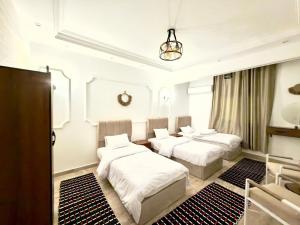 a bedroom with three beds and a chandelier at TriPyramids Suites in Cairo