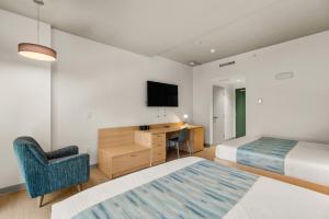 a hotel room with two beds and a desk and a tv at The Simon at Simon Fraser University in Burnaby