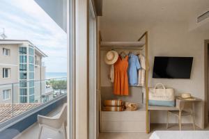 a room with a balcony with a bed and a television at Frontemare Appartamenti e Camere ELISABETTA in Cesenatico