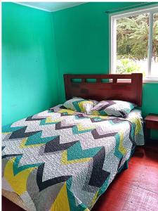 a bed in a bedroom with a green wall at Cabañas "Parada Tentelhué" in Rolecha