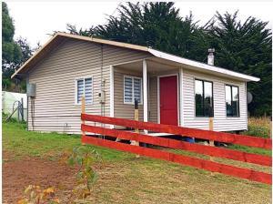 a small house with a red fence in front of it at Cabañas "Parada Tentelhué" in Rolecha