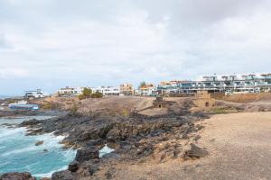 a group of buildings on a rocky beach with the ocean at Cotillo Jolanda in El Cotillo