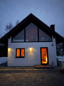 a white house with two windows and lights on it at Domek pod Besidą in Czarna