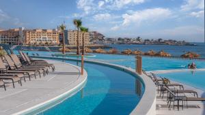 a large swimming pool with chairs and the ocean at Elegant Beachfront Getaway with Unmatched Views in Puerto Peñasco