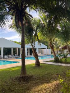 two palm trees in front of a swimming pool at STEPS TO THE BEACH 2 Stunning condo 4 min walk to Bibijagua Beach and Catamarans in Punta Cana